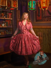 Pinup girl in a tiki bar wearing pink polynesian style midcentury modern vintage style swing dress.