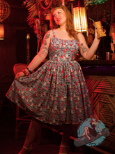 Redhead pinup girl at tiki bar wearing blue 1950s vintage style sundress with sailboat pattern.
