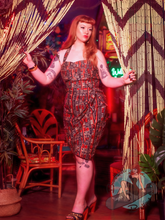 Redhead Pinup Girl at tiki bar wearing black and orange 1950s sarong dress in style of vintage Alfred Shaheen dresses.