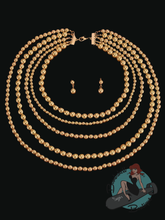 Gold beaded necklace and earrings on a black background