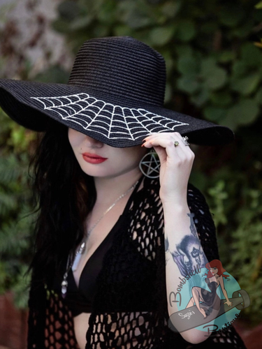 Goth pinup wearing large brim floppy sunhat with spiderweb embroidery on it