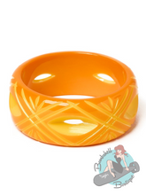 Orange bracelet with a wavy pattern on a white background, featuring a brand logo in the corner.