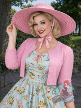 Pinup girl wearing swing dress with vintage style wide brim straw hat